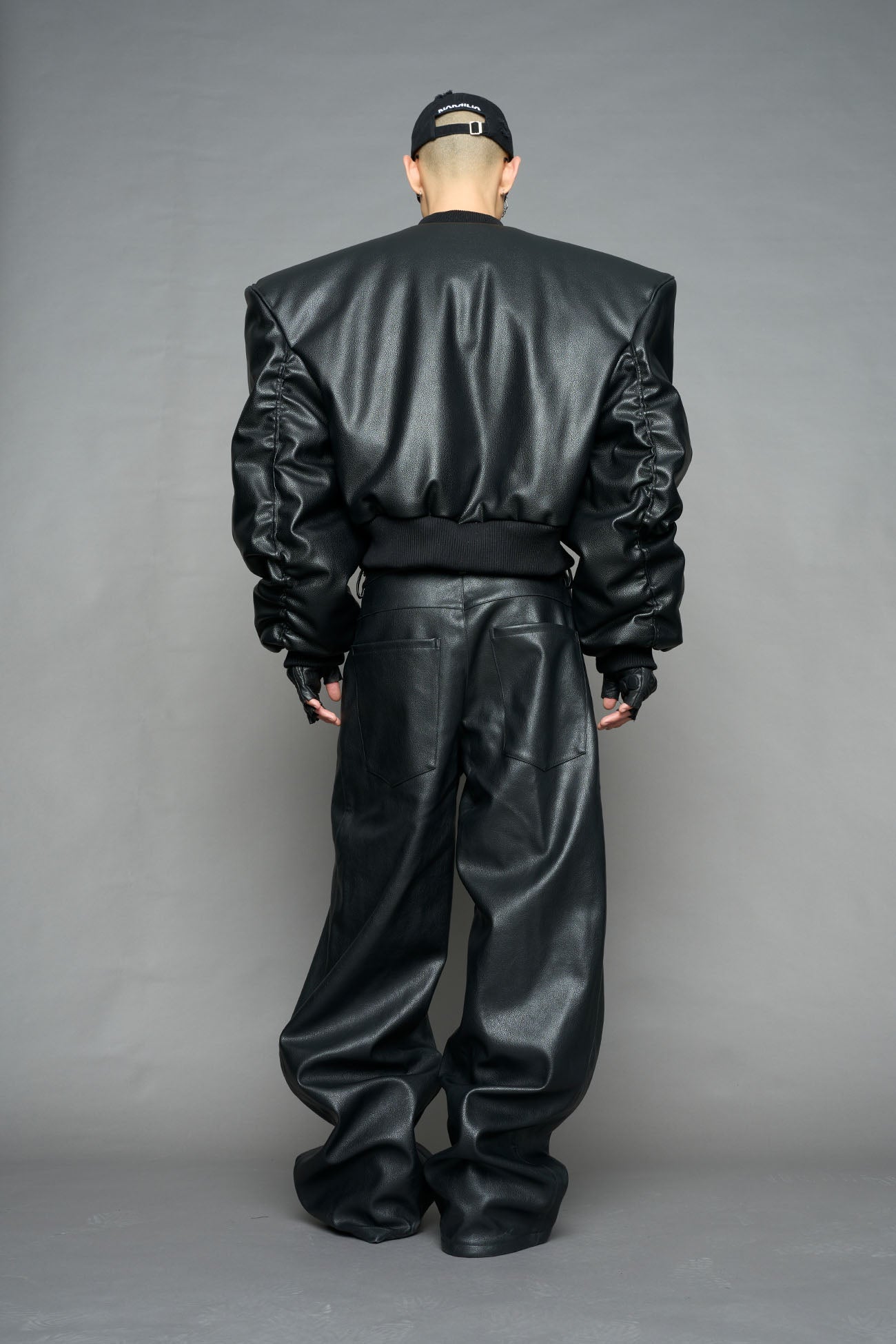 model wearing black vegan leather bomber jacket with large shoulders