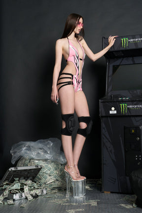 Model wears a pink panelled vegan leather bodysuit with deep V neckline, open back, flame stitching, and slogan embroidery.