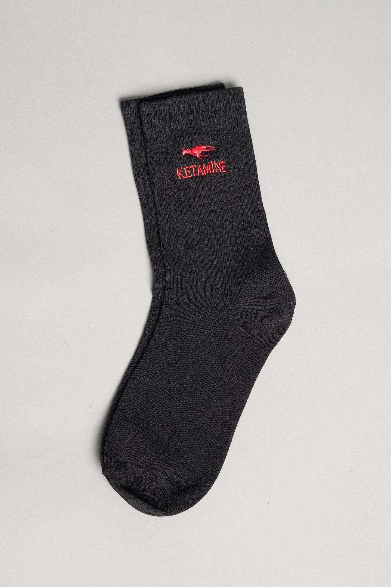 Black ribbed sport socks with red embroidered dragon and bold ‘KETAMINE’ slogan by Namilia, unisex mid-calf fit.