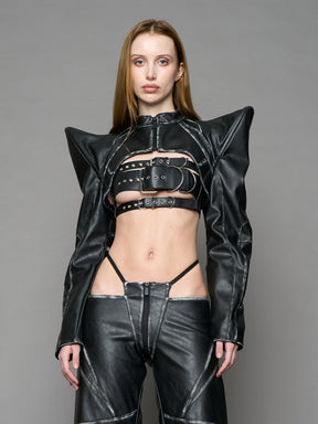 Model wearing a black vegan leather spike shoulder bolero jacket with cut-out design on a gray background