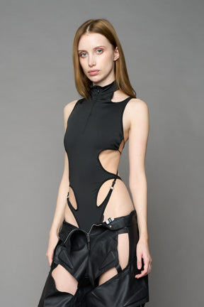 Black cut-out bodysuit by NAMILIA with high neckline, front zip, adjustable straps, and metal ring detailing