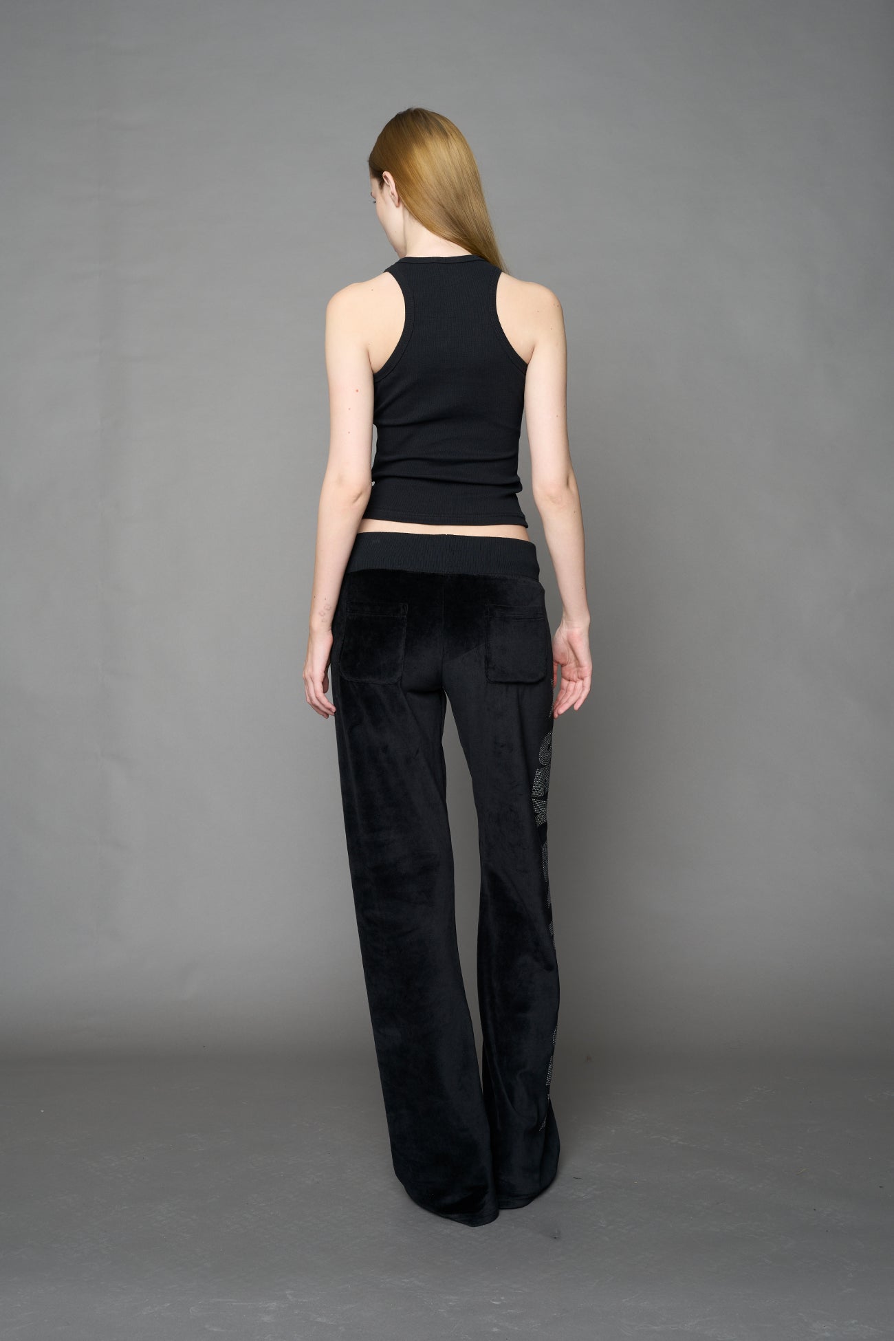 Black velour pants with NAMILIA x Symbol rhinestone detailing and a fitted straight-leg silhouette