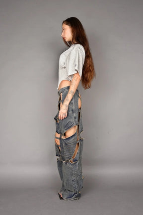 Person wearing a grey crop top and ripped jeans on a gray background