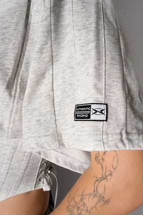 Person wearing a grey crop top and ripped jeans on a gray background