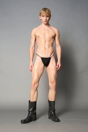 model wearing black thong with metal crucifix back