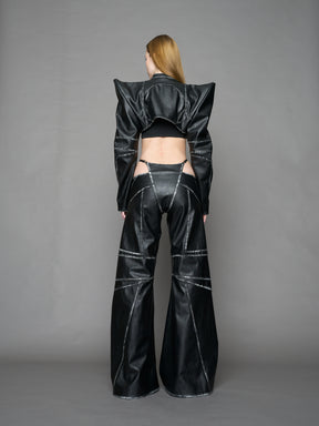 Person wearing a black thong pants with wide-legs and a jacket on a gray background