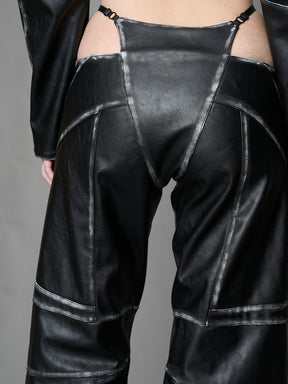 Person wearing a black thong pants with wide-legs and a jacket on a gray background