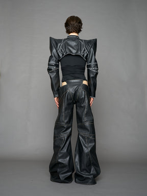 Person wearing a black thong pants with wide-legs and a jacket on a gray background