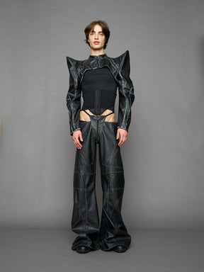 Model wearing a black vegan leather spike shoulder bolero jacket with cut-out design on a gray background