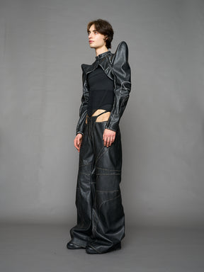 Person wearing a black thong pants with wide-legs and a jacket on a gray background