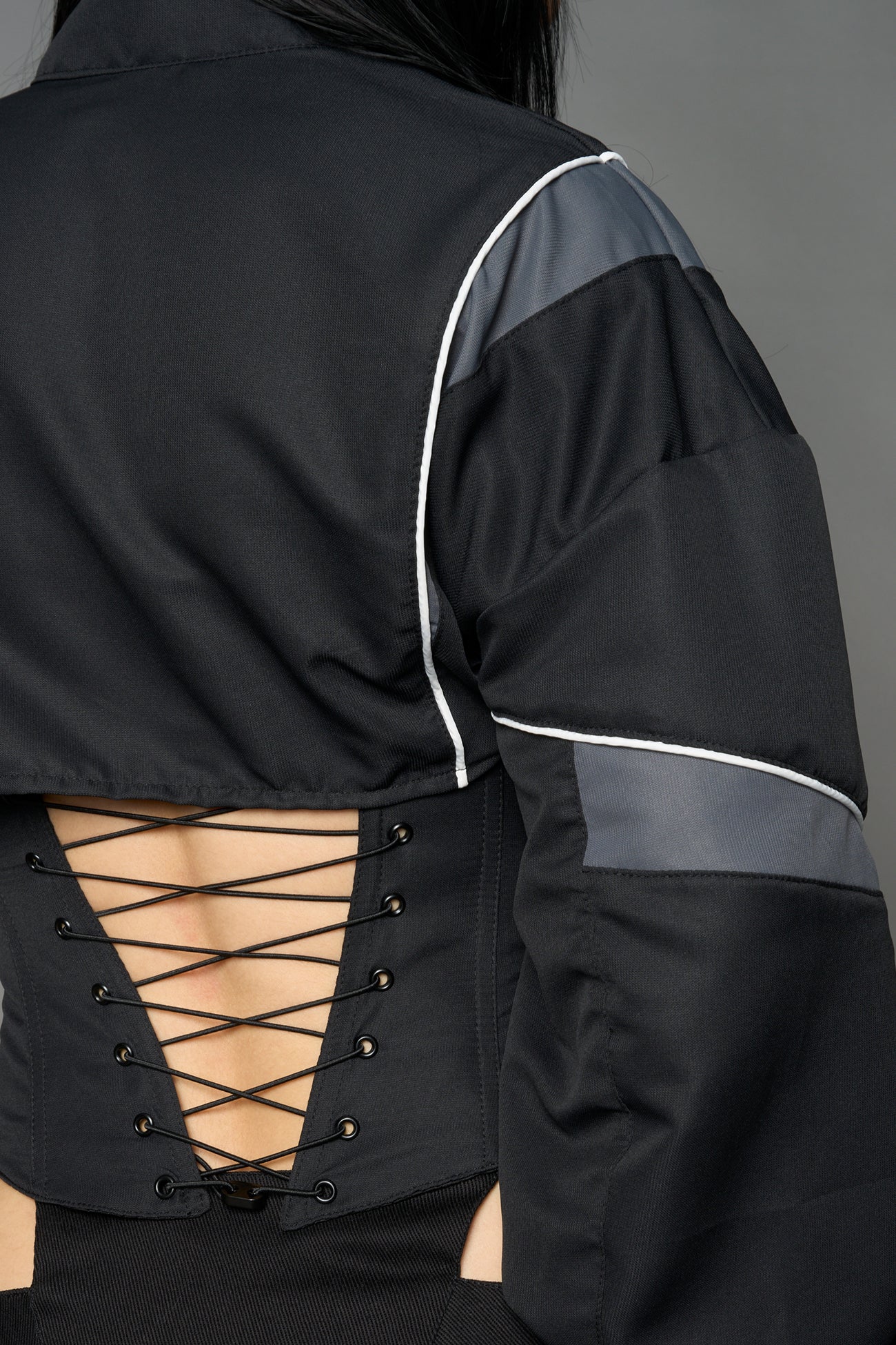 Black Namilia tracksuit jacket with grey sleeve stripes and lace-up corset back