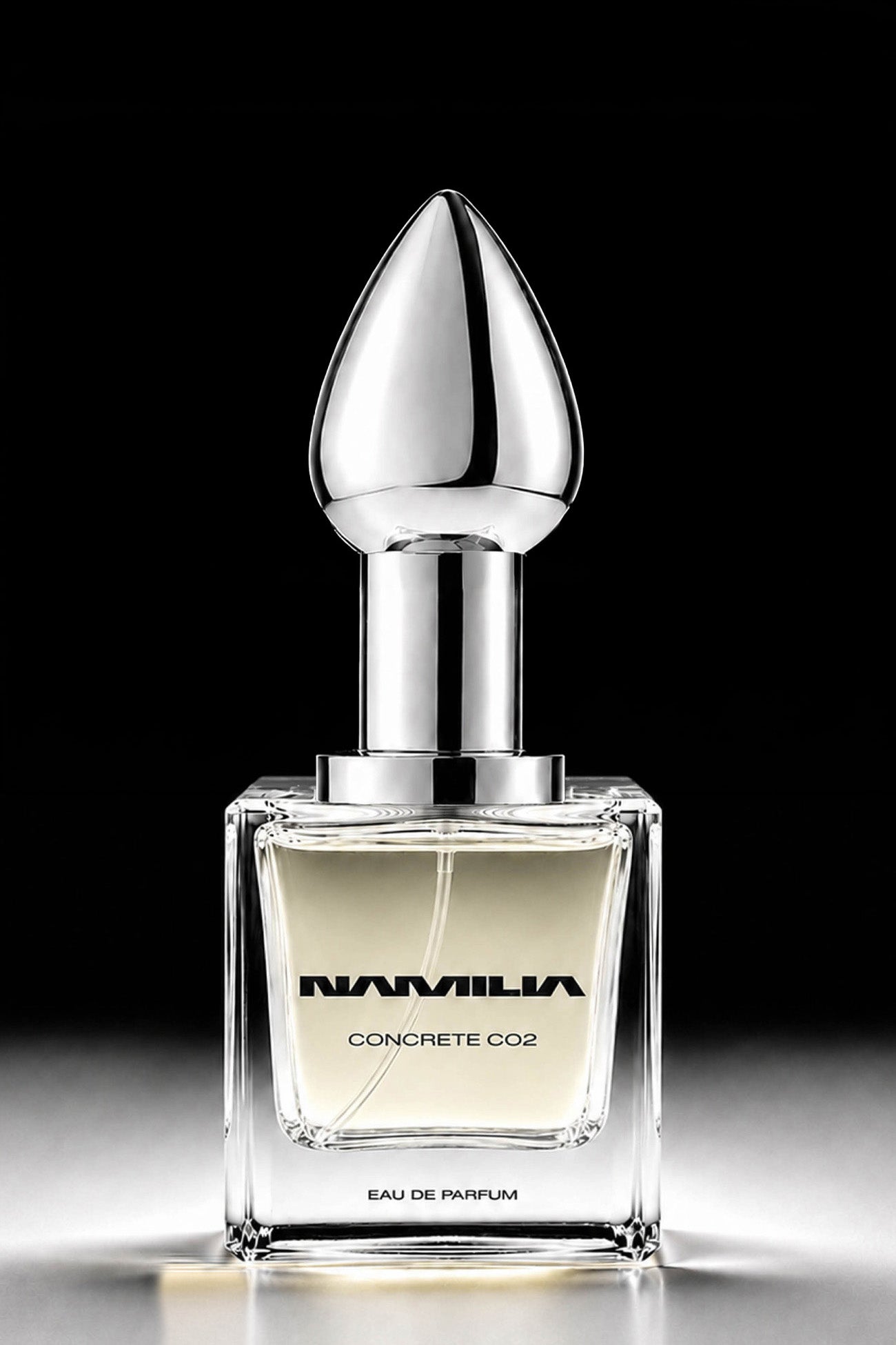 A bottle of Namilia Concrete CO2 Eau de Parfum with a large reflective black plug-shaped cap