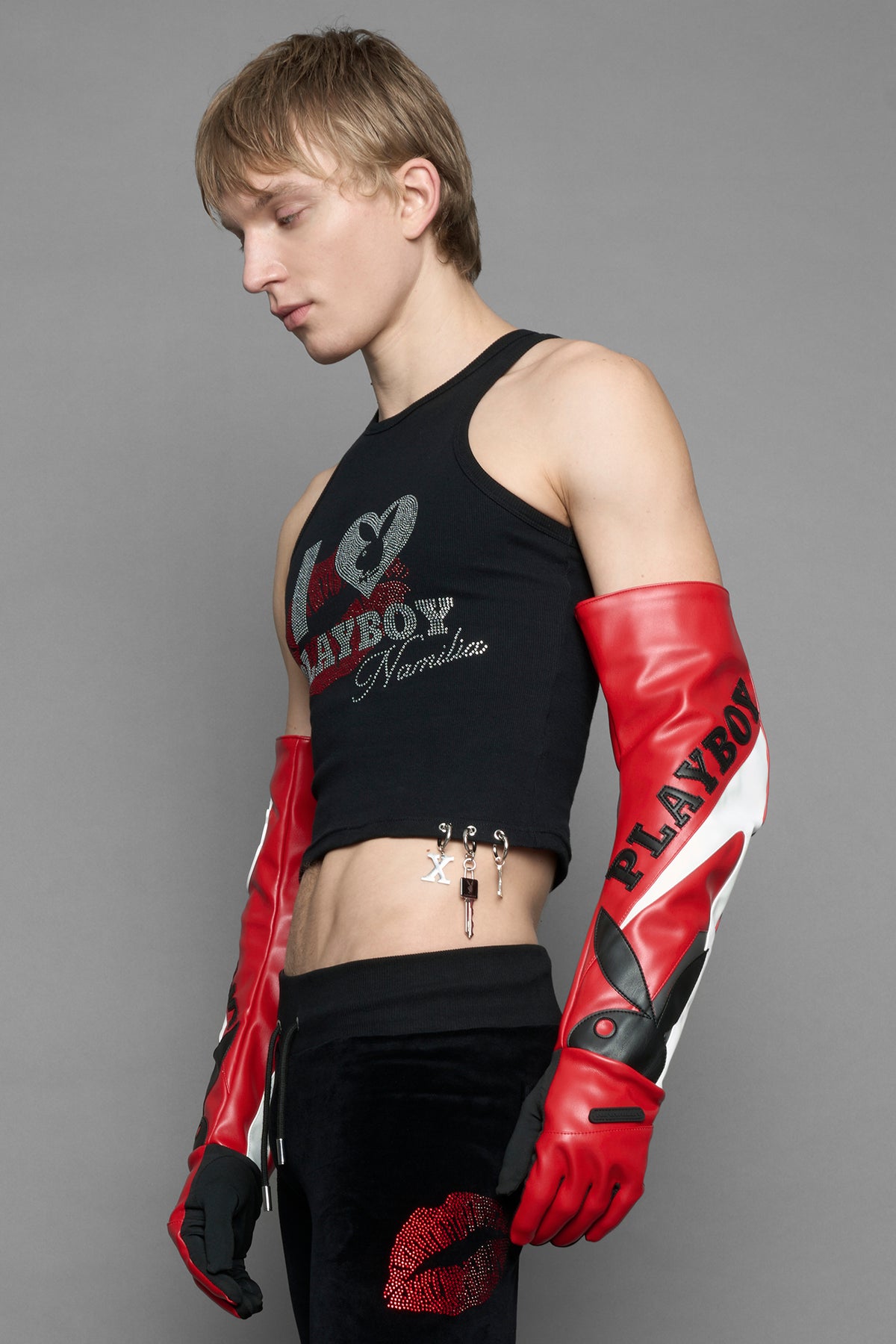 A model wears long motocross inspired red vegan Leather gloves with white and grey style paneling and black PU Leather 'Namilia' and 'Playboy' embroidery and a 'Playboy x Namilia' Rubbertag.