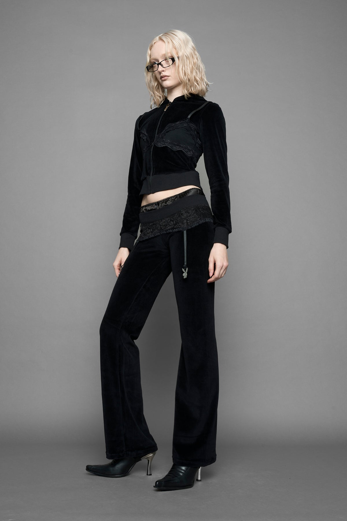 model is wearing a black velvet cropped zip-up hoodie with a black lace bralette and a Playboy branded key formed Zipper Pull 