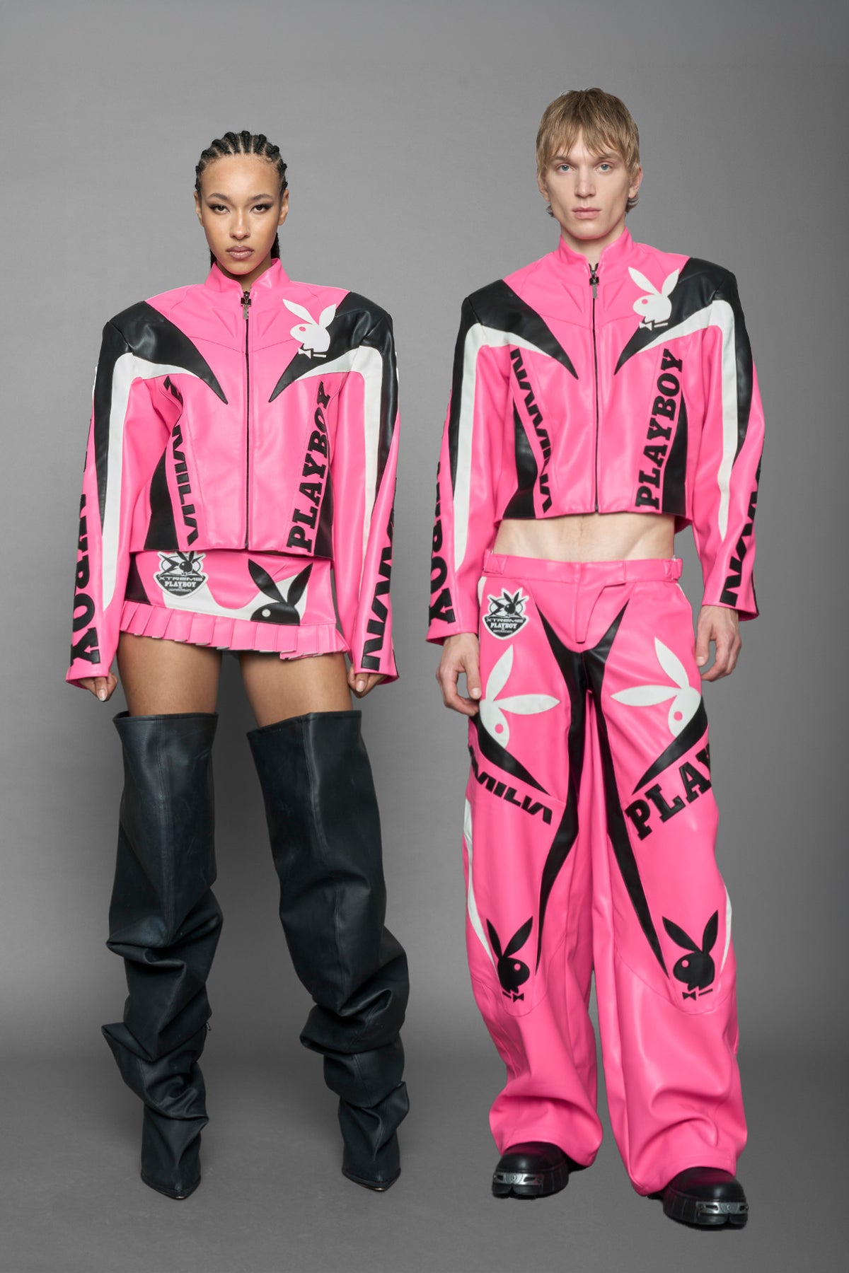 model wearing pink vegan leather zip-up jacket with black PU leather 'Namilia' and 'Playboy' embroidery and black and white paneling. On the left chest there is a white Playboy Bunny Embroidery.