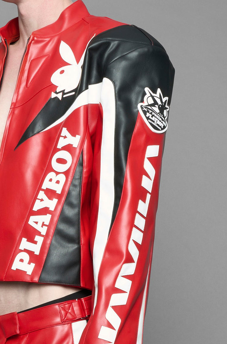 model wearing red vegan leather zip-up jacket with black PU leather 'Namilia' and 'Playboy' embroidery and black and white paneling. On the left chest there is a white Playboy Bunny Embroidery.