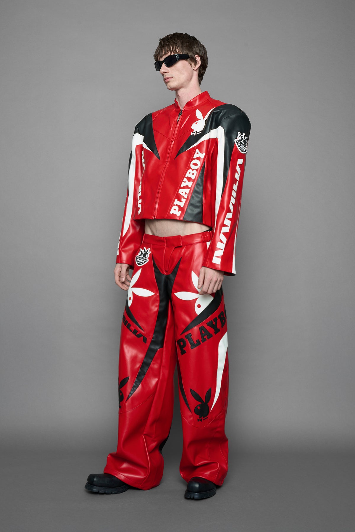 model is wearing red PU Leather pants with bold white Playboy bunny logos and white 'Namilia' Embroidery and rubber tag.