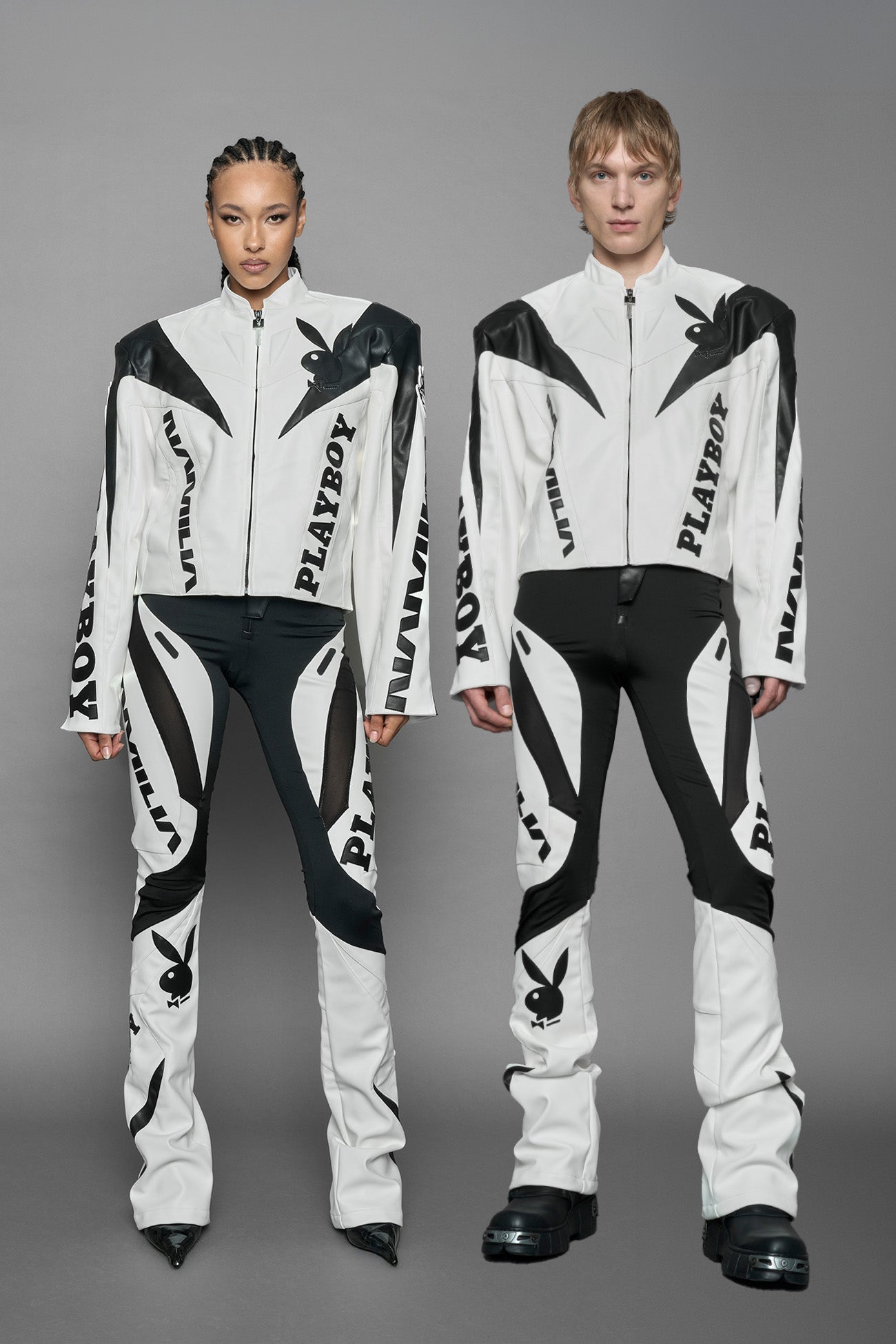 model wearing white vegan leather zip-up jacket with black PU leather 'Namilia' and 'Playboy' embroidery and black and white paneling. On the left chest there is a white Playboy Bunny Embroidery.