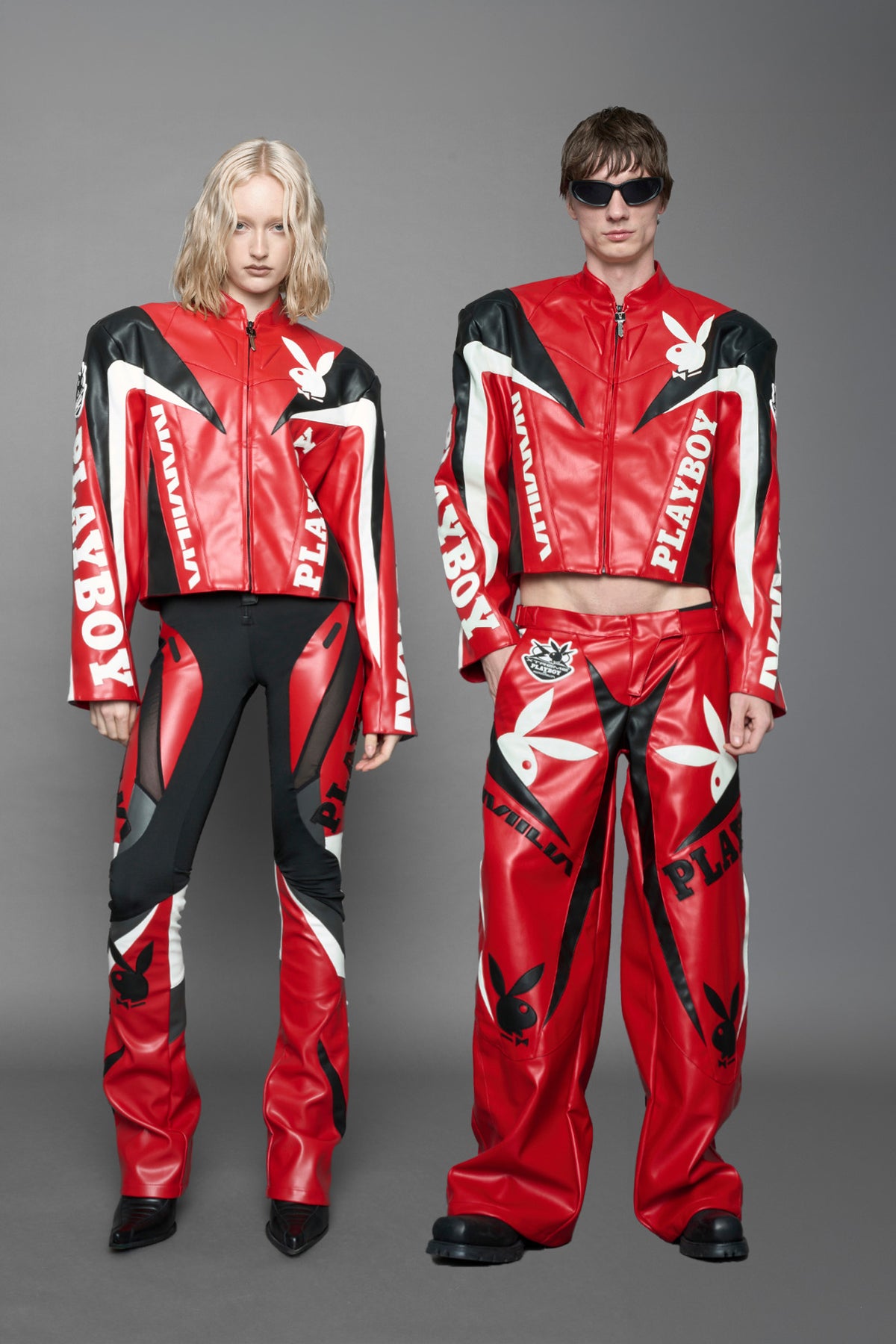 model wearing red vegan leather zip-up jacket with black PU leather 'Namilia' and 'Playboy' embroidery and black and white paneling. On the left chest there is a white Playboy Bunny Embroidery.