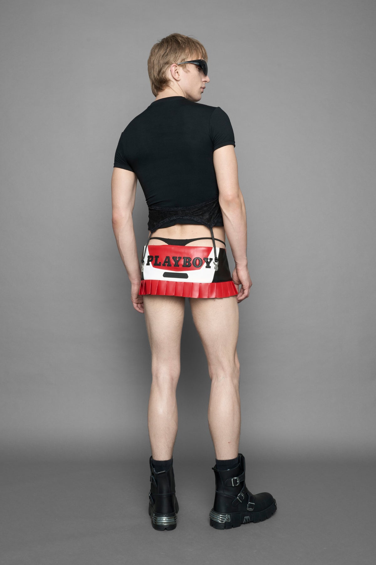 model wearing a black short-sleeve graphic t-shirt with rhinestone embroidery of red lip print and silver 'I <heart> PLAYBOY' design. T-Shirt has a lingerie black lace garter with suspender with metal silver Bunny Heads attached.