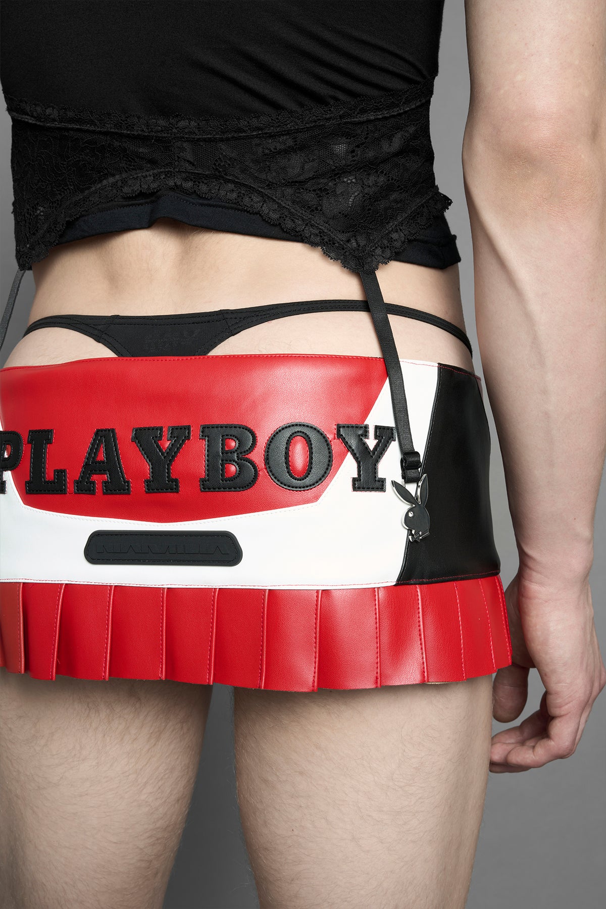 model wearing a red vegan leather wrap mini skirt with a black PU leather Bunny embroidery and a branded 'Playboy X Namilia' Rubbertag.