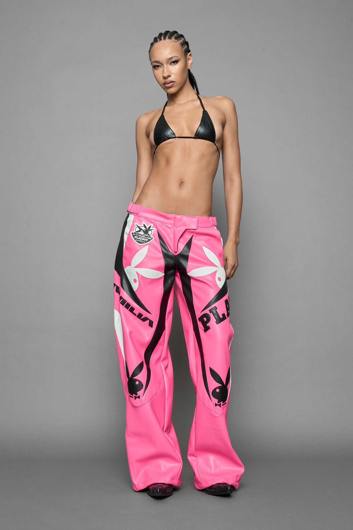 model is wearing pink PU Leather pants with bold white Playboy bunny logos and white 'Namilia' Embroidery and rubber tag.