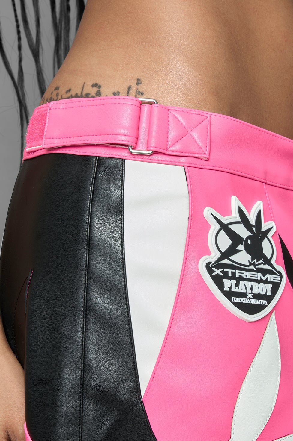 model is wearing pink PU Leather pants with bold white Playboy bunny logos and white 'Namilia' Embroidery and rubber tag.