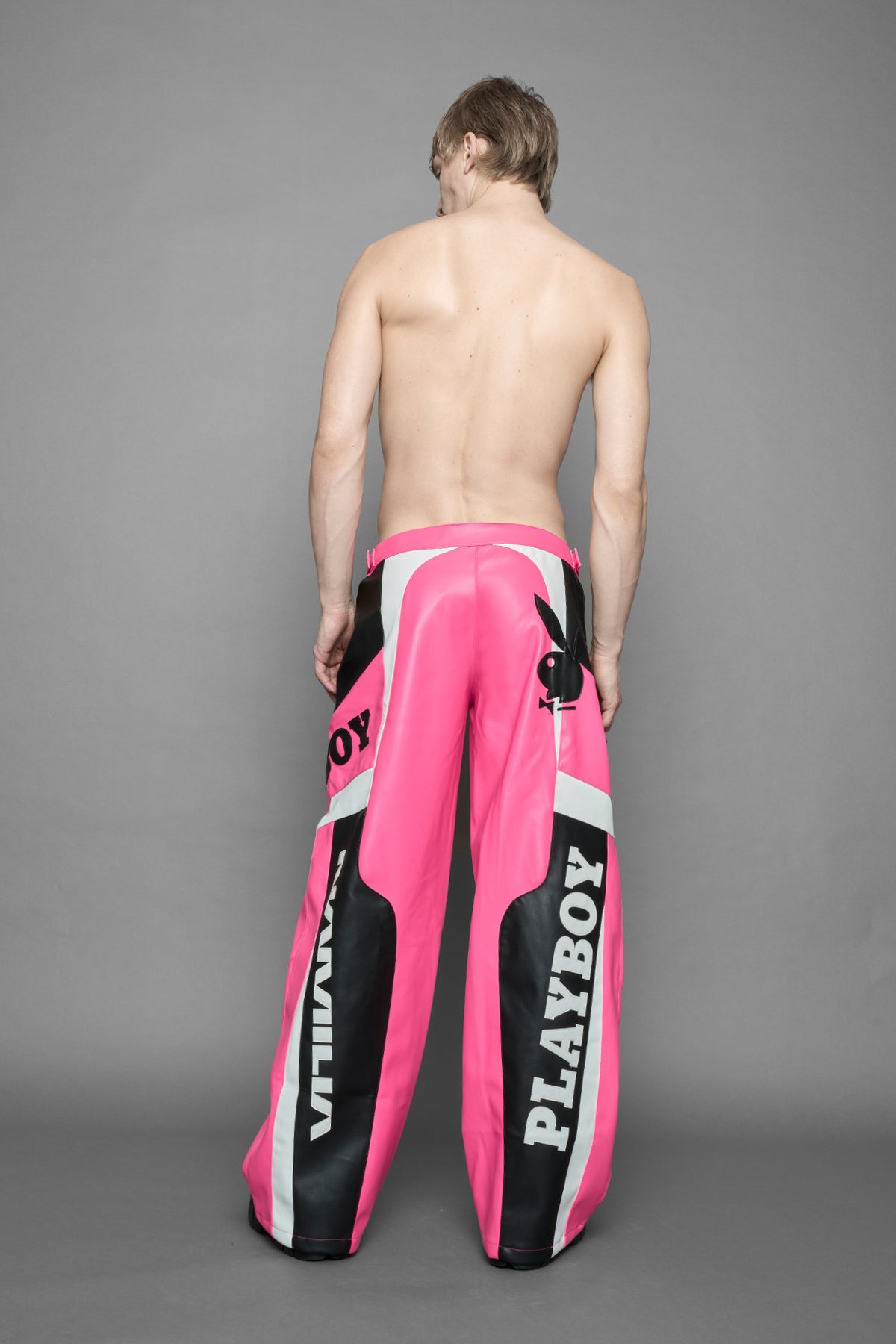 model is wearing pink PU Leather pants with bold white Playboy bunny logos and white 'Namilia' Embroidery and rubber tag.