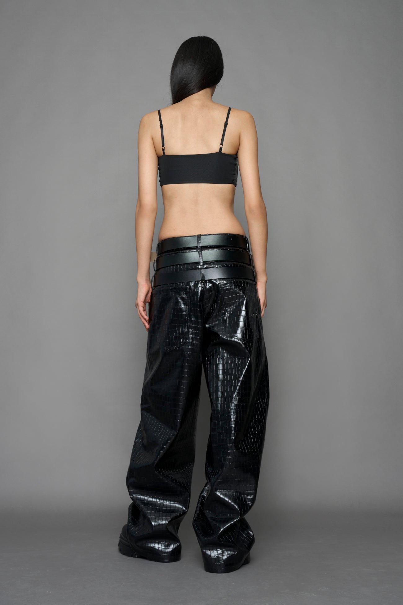 model wearing black vegan leather croc inspired belt top with buckle details